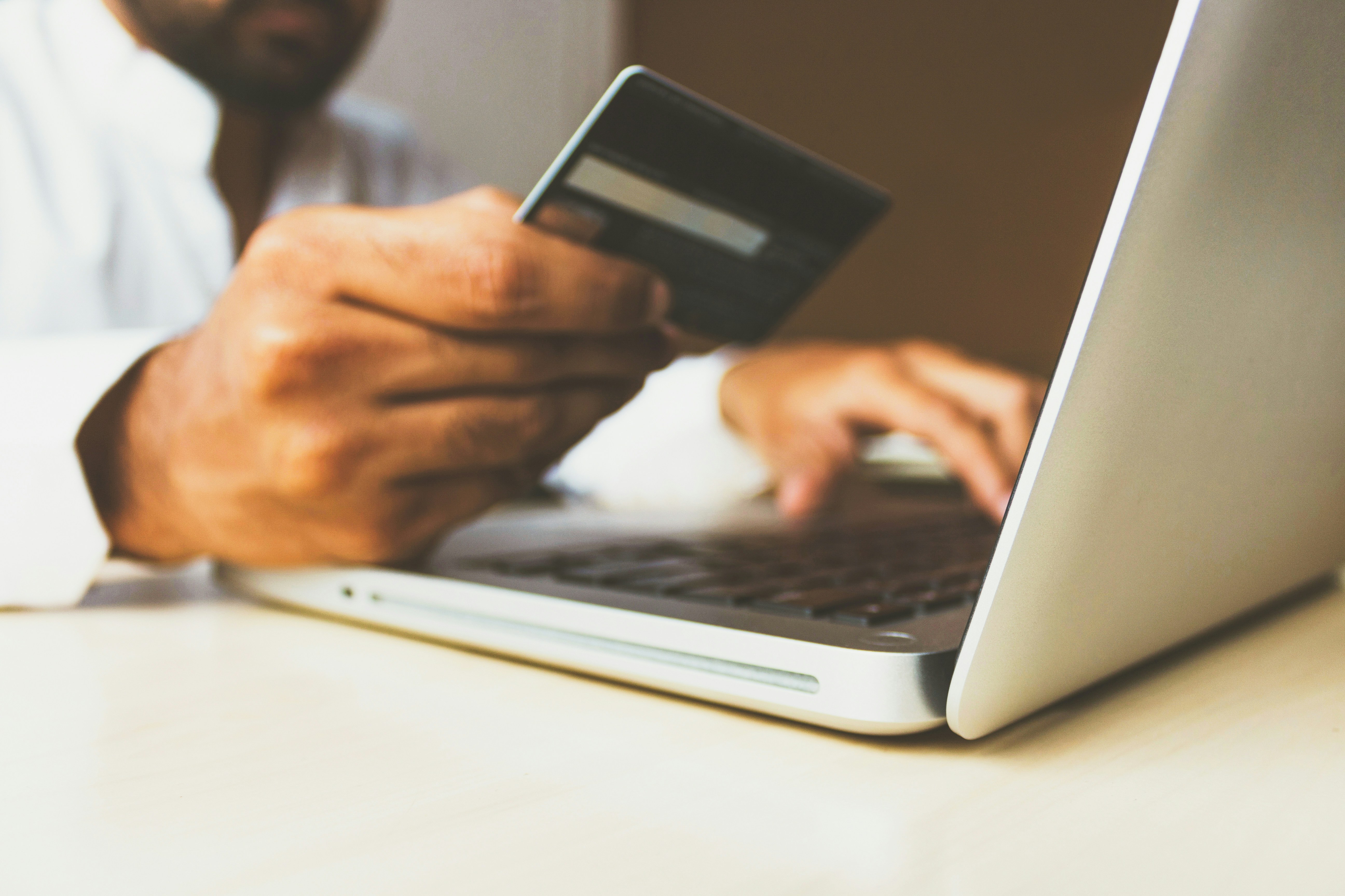 Person with credit card typing on laptop.